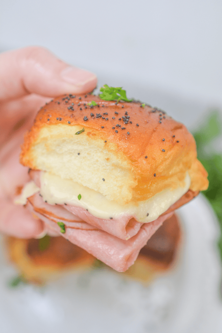 Air fryer Hawaiian ham and cheese sliders on a wooden serving board garnished with poppy seeds
