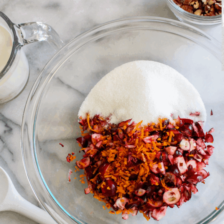 Folding fresh cranberries, sugar, and orange zest into scone dough on a floured surface