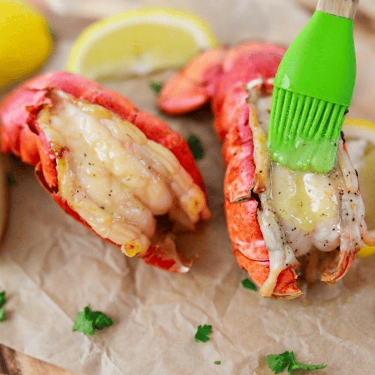 Air fryer lobster tails brushed with lemon garlic butter on a serving plate