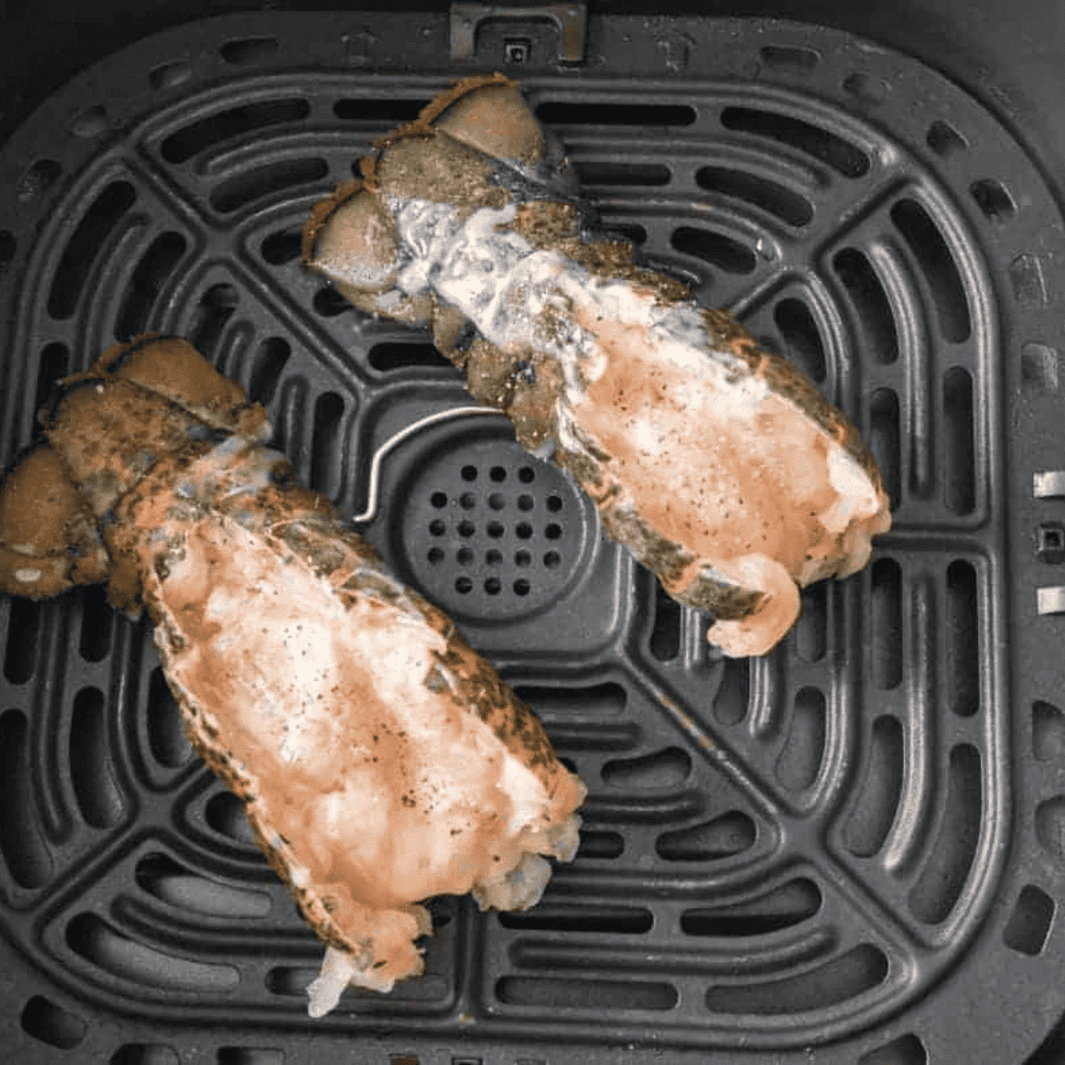 Lobster tails cooking in air fryer with melted butter glaze