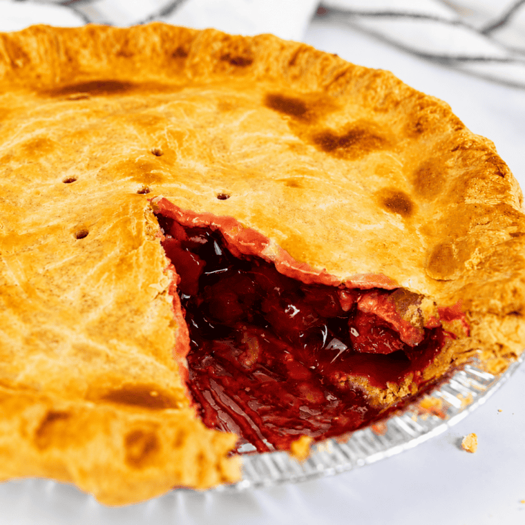 Slice of air fryer cherry pie on a plate topped with a scoop of melting vanilla ice cream