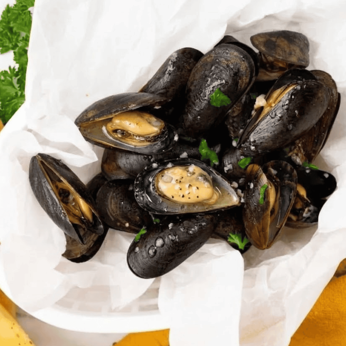 Air fryer mussels cooked in garlic butter sauce, served hot with herbs and crusty bread for dipping.