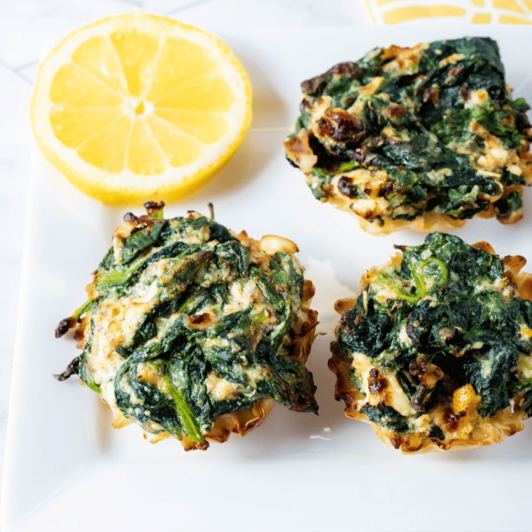 Golden crispy air fryer spanakopita phyllo cups filled with spinach and feta on a serving platter.