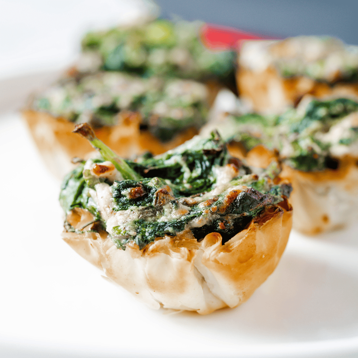 Golden air fryer spanakopita phyllo cups filled with creamy spinach and feta on a serving plate.