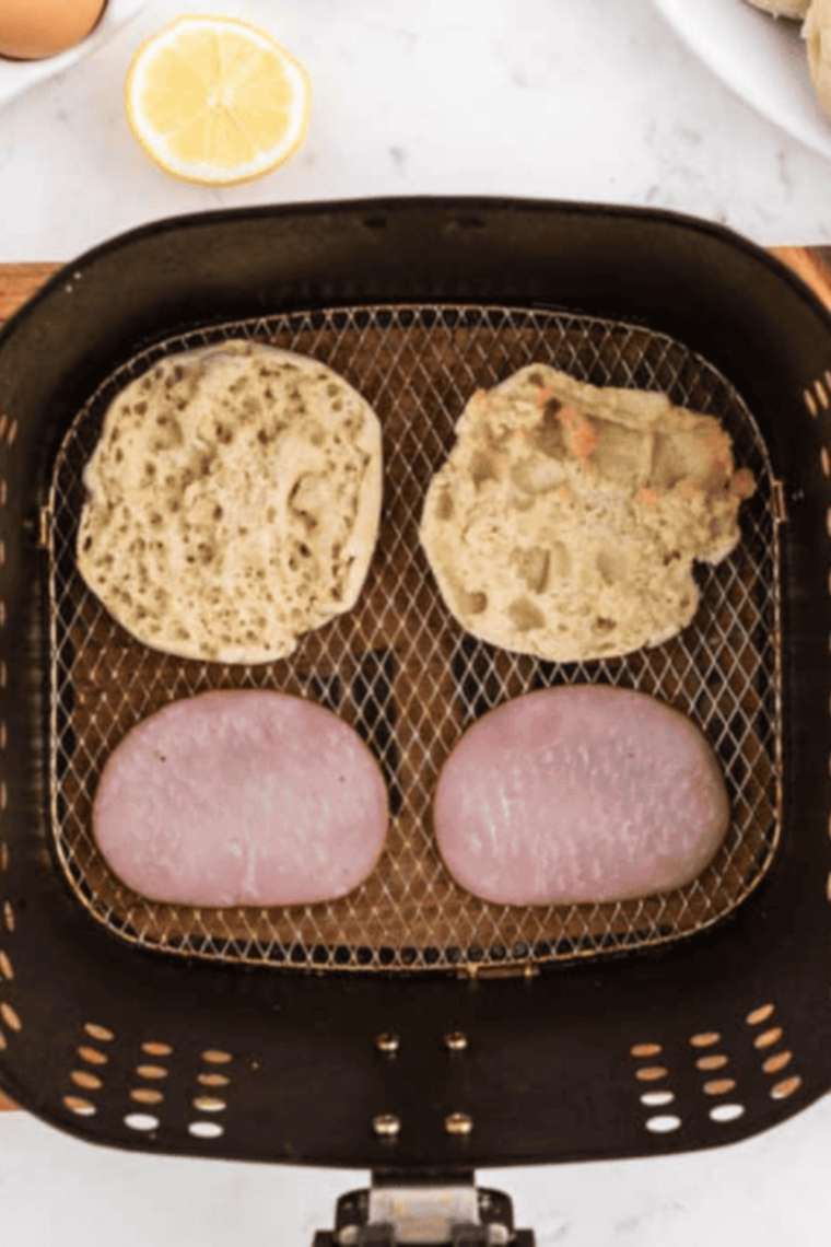 Air frying English muffins and Canadian bacon at 400°F until golden edges and heated through then keeping warm under foil or low oven until ready to serve