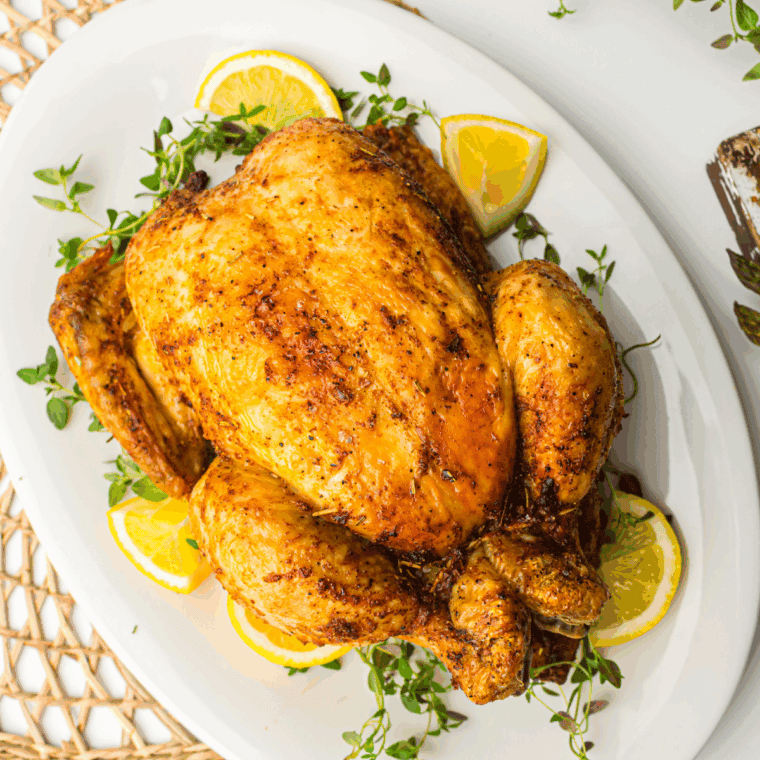 Golden-brown roasted Amish whole chicken on a platter, garnished with fresh herbs, ready to serve.