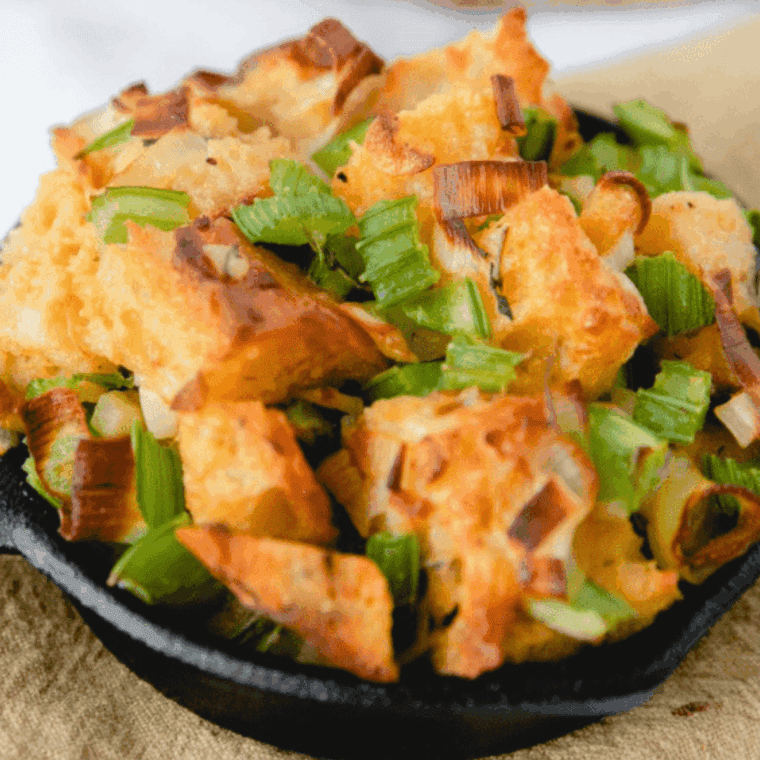 Cornbread dressing in a foil-covered dish going into the air fryer basket