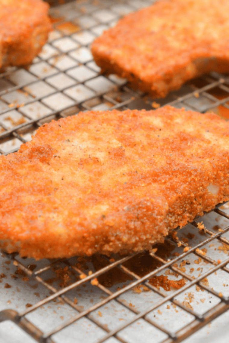 Close-up of baked Shake & Bake chicken coated in BBQ seasoning, showing crunchy texture and sticky glaze with a fork breaking a piece open.