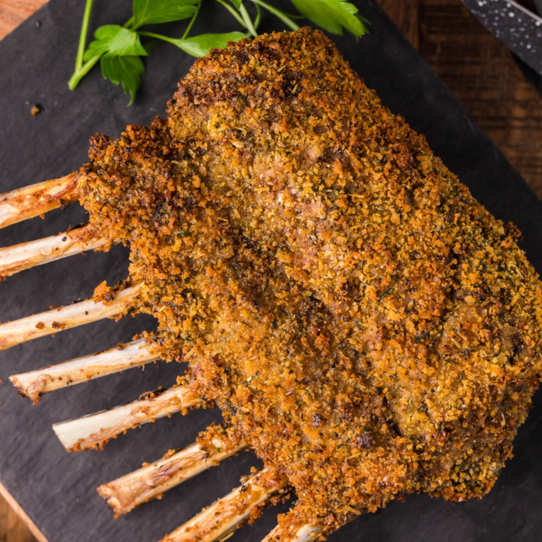 Air fryer rack of lamb with a golden garlic-herb crust, garnished with fresh rosemary on a white plate