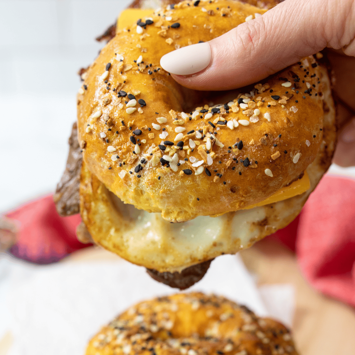 Air fryer bagel breakfast sandwich with a baked egg, sausage patty, and melted cheese on a homemade bagel
