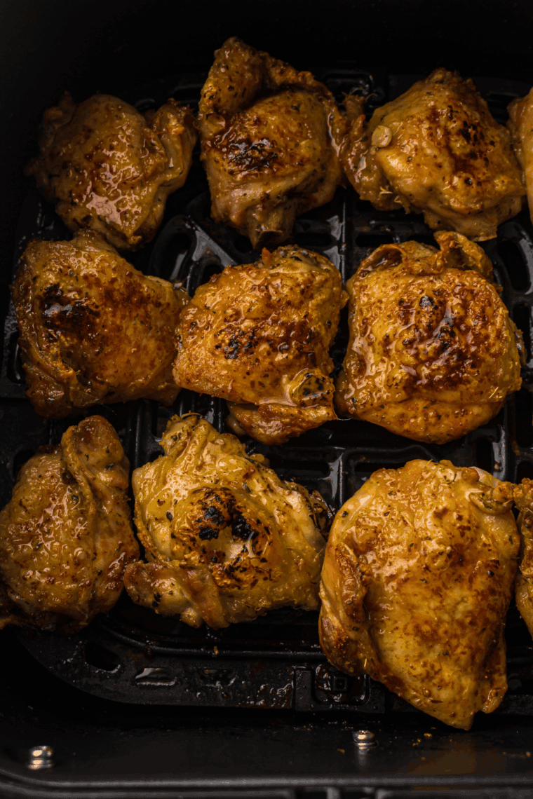 Golden, crispy air fryer lemon garlic chicken thighs garnished with fresh lemon slices and parsley.