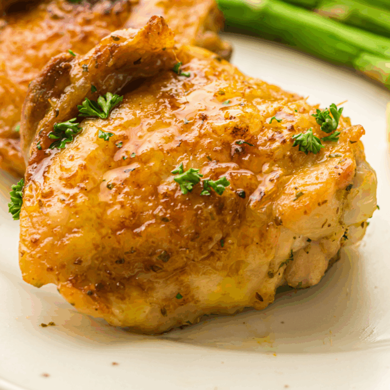 Golden, crispy air fryer lemon garlic chicken thighs garnished with fresh lemon slices and herbs.