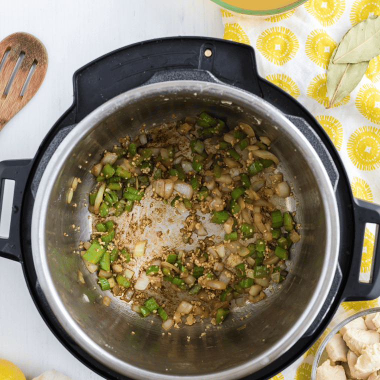 Diced onion, celery, and garlic sautéing in olive oil in the Instant Pot for Greek lemon chicken soup