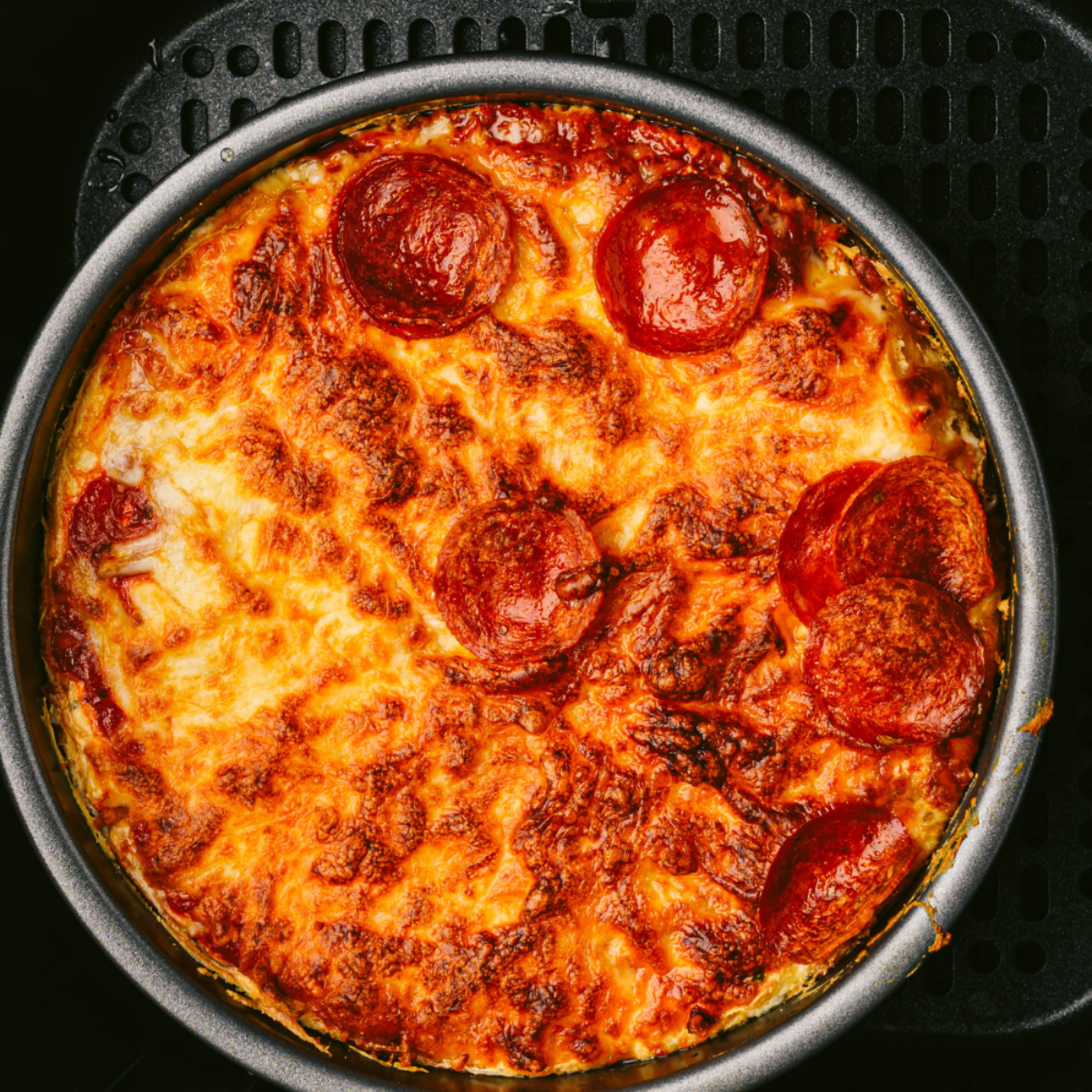 Air fryer bubble-up pizza bake with biscuit dough pepperoni and melted mozzarella cheese
