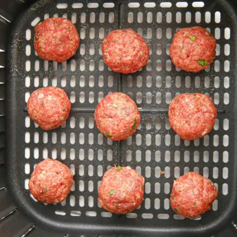 Raw meatballs spaced in a single layer in an air fryer basket