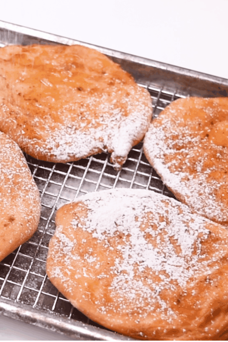 Air fryer fried dough being brushed with melted butter and dipped in cinnamon sugar.