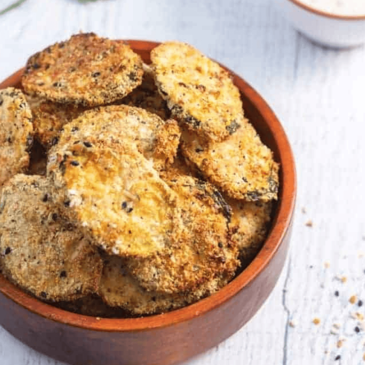 Extra crispy breaded keto zucchini chips fresh from the air fryer, served on a plate.