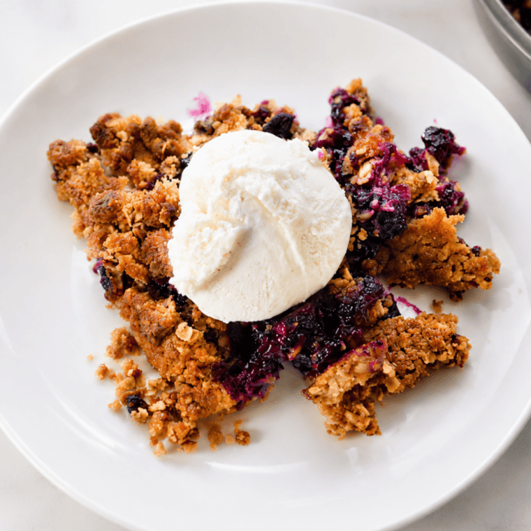 Air fryer blueberry crisp with a golden oat crumble topping in a white baking dish