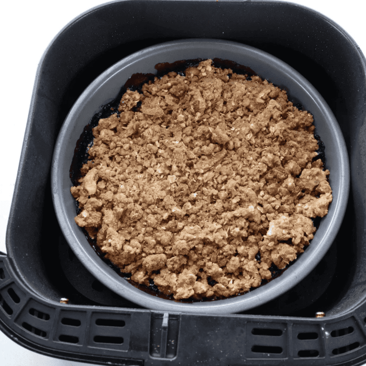 Unbaked blueberry crisp topped with oat crumble in an air fryer pan