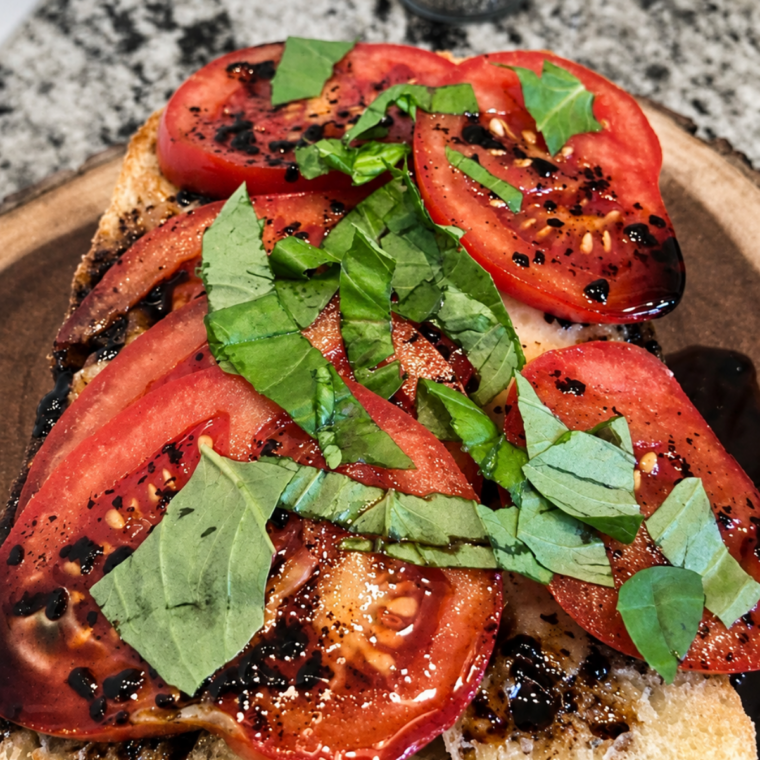 Air fryer caprese garlic bread topped with melted mozzarella, sliced tomatoes, fresh basil, and balsamic glaze