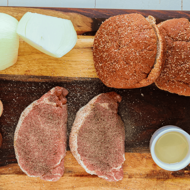 Ingredients for air fryer Chicago-style pork chop sandwiches laid out — boneless pork chops, two onions, hamburger buns, oil, salt, and pepper.