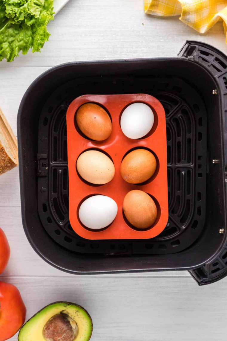 Whole eggs on a trivet in the air fryer basket before cooking