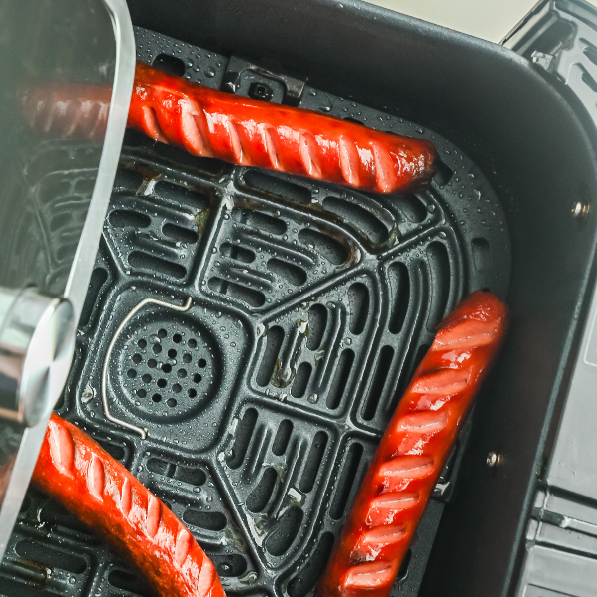 air fryer hot dogs with scored casings in basket, golden brown exterior