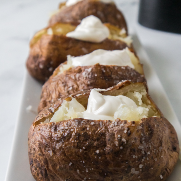 Air fryer jacket potato split open with butter melting into the fluffy middle