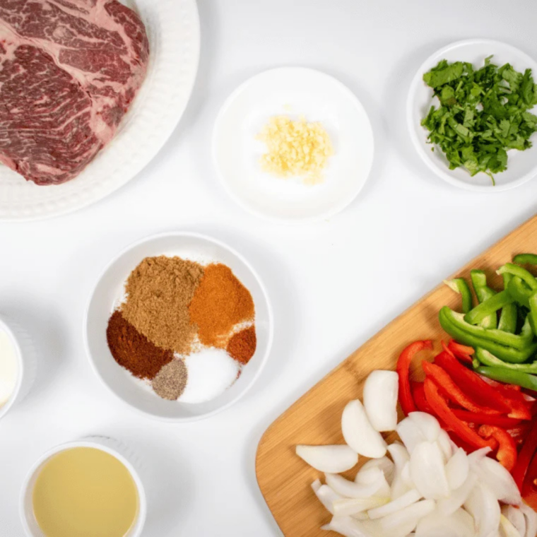 Ingredients for air fryer steak tacos: ribeye steak, taco seasoning, lime, garlic, olive oil, and tortillas