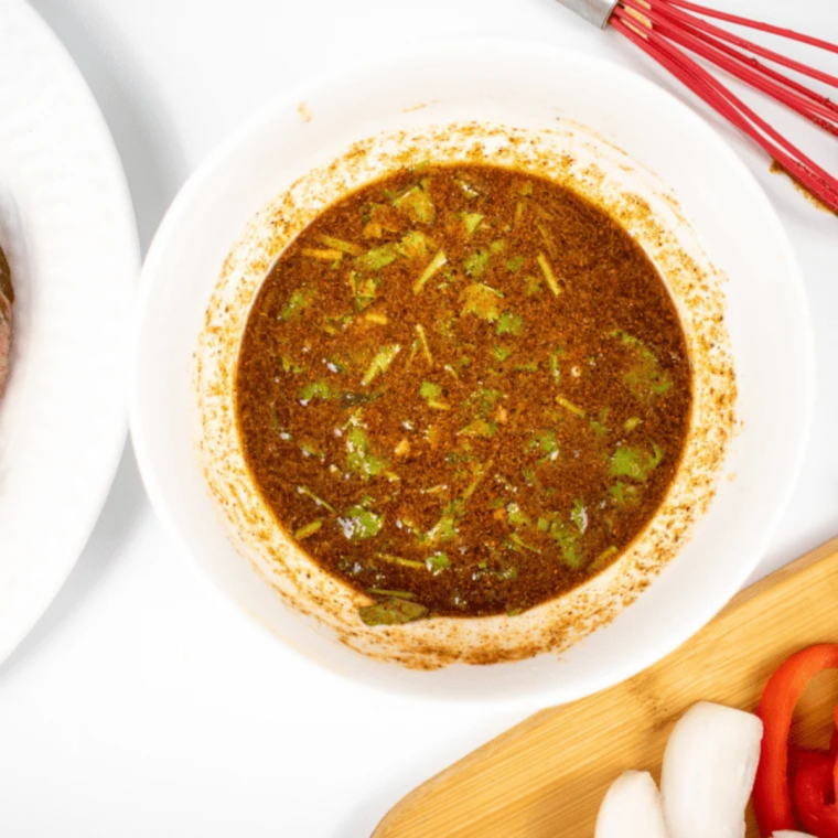 Taco seasoning, lime juice, garlic, and olive oil whisked into a marinade with ribeye steak in a dish