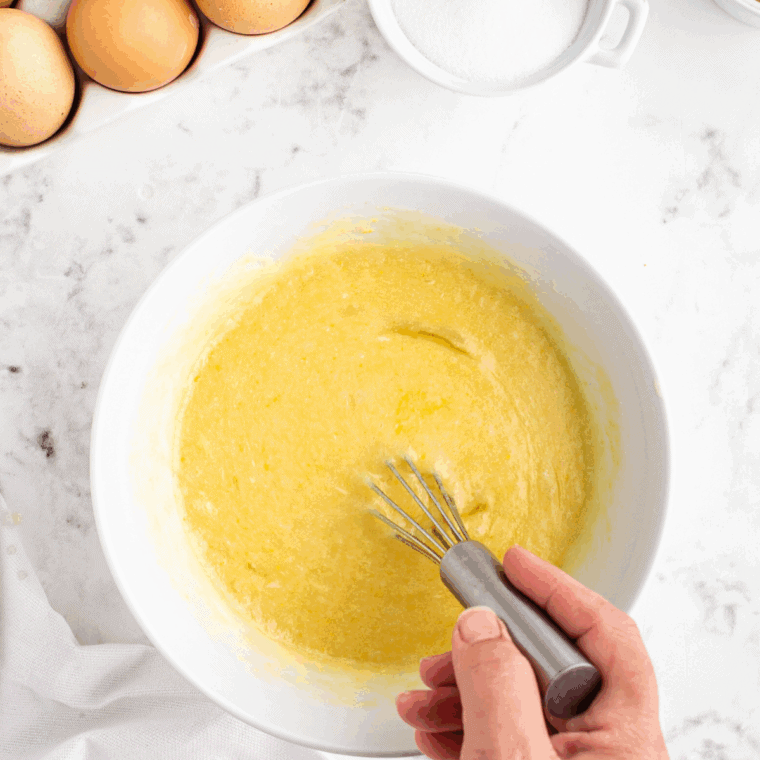 Mixing flour, poppy seeds, butter, sugar, eggs, sour cream, milk, lemon juice, and vanilla together in a large bowl to form muffin batter