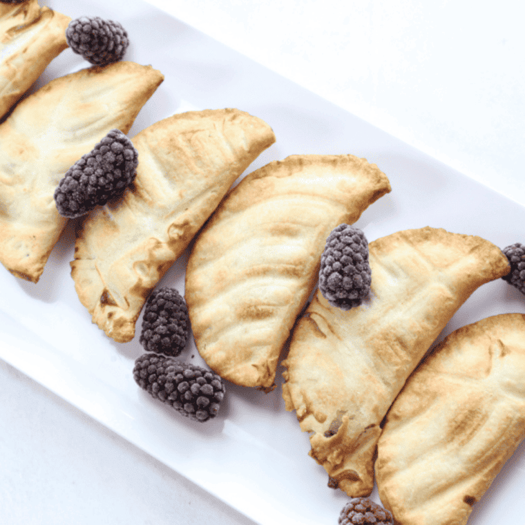 Golden air fryer blueberry hand pies with flaky crust and sweet blueberry filling, topped with vanilla glaze
