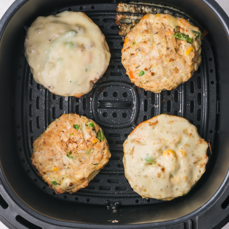 Slice of cheddar melting over a chicken patty during the final minutes in the air fryer