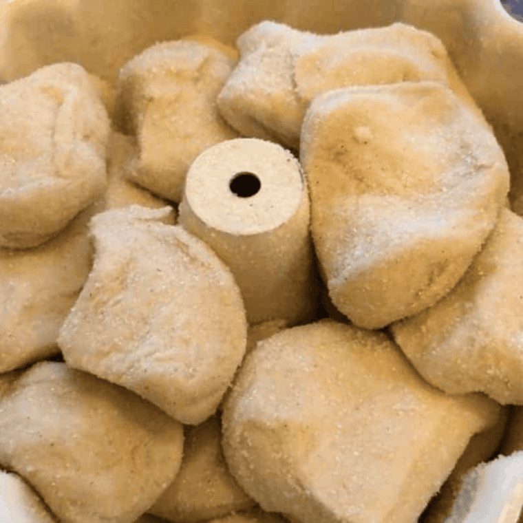 Cinnamon sugar coated biscuit pieces layered loosely in a greased bundt pan for air fryer monkey bread