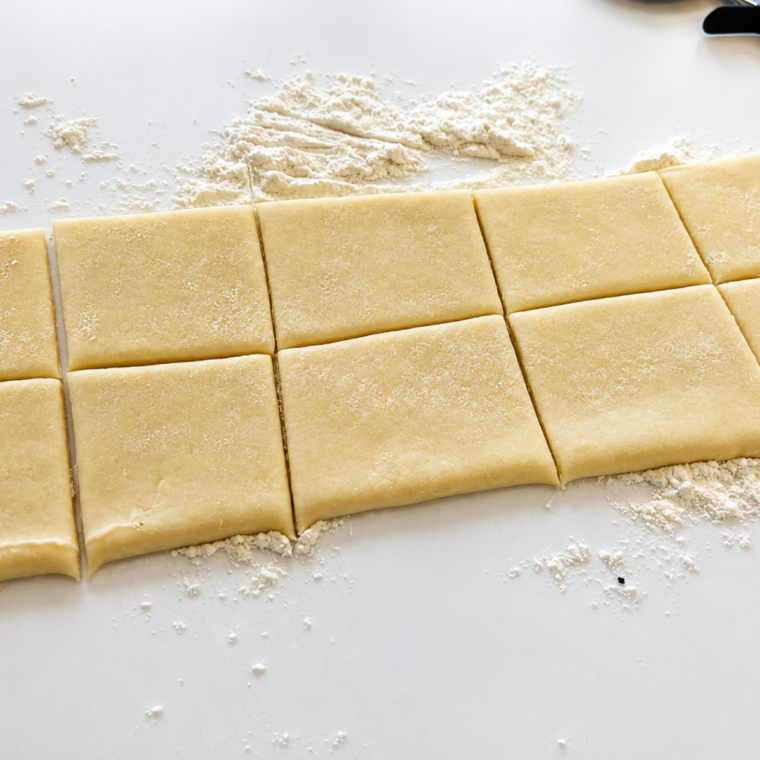 Sheet of puff pastry unfolded on a lightly floured counter, ready to be cut into squares