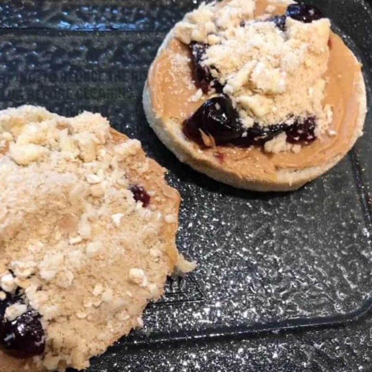 English muffins topped with peanut butter, jelly, and crumbly oat streusel cooking in the air fryer.