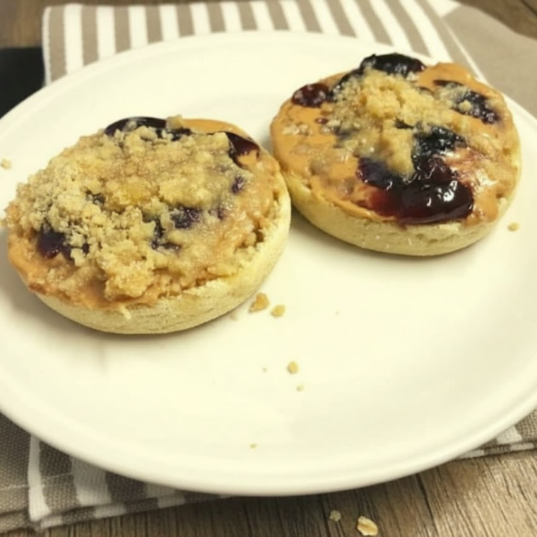 Air fryer toasted English muffins topped with peanut butter, jelly, and golden oat streusel crumble.