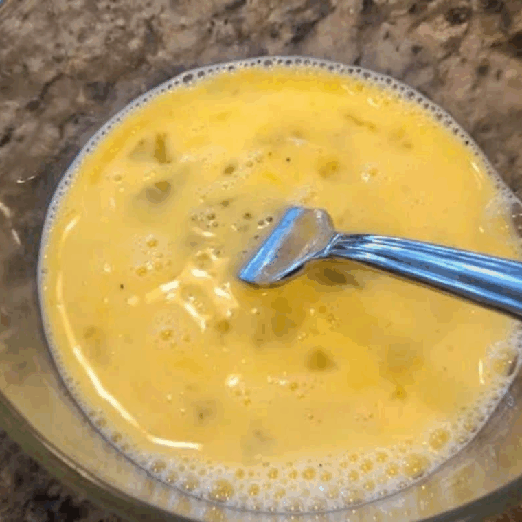 Cracking fresh eggs into a small mixing bowl, ready to whisk