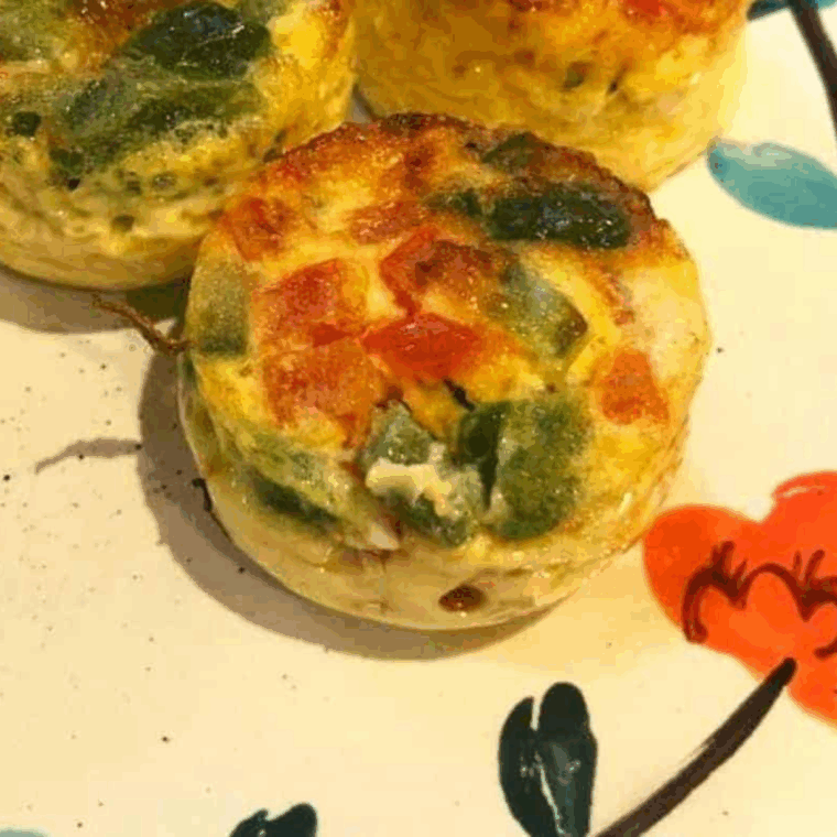 Air Fryer Western Omelet Egg Bites with ham, bell peppers, onions, and cheddar cheese served on a plate for an easy breakfast idea.