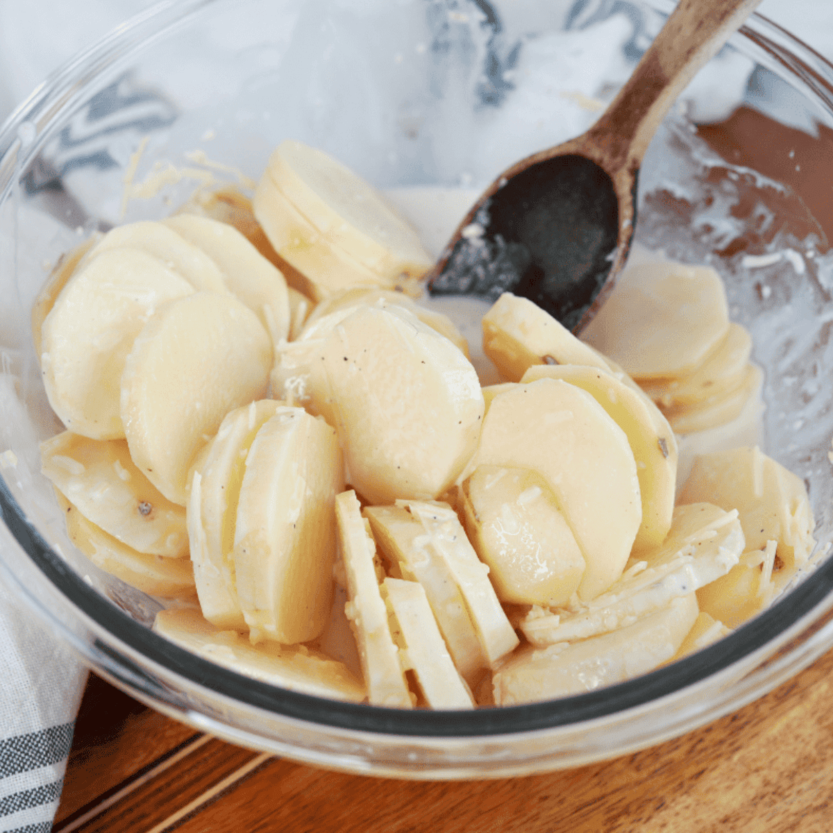 Air fryer pan greased and potatoes sliced, tossed with milk, cream, Parmesan, garlic, nutmeg, salt, and black pepper in a large bowl