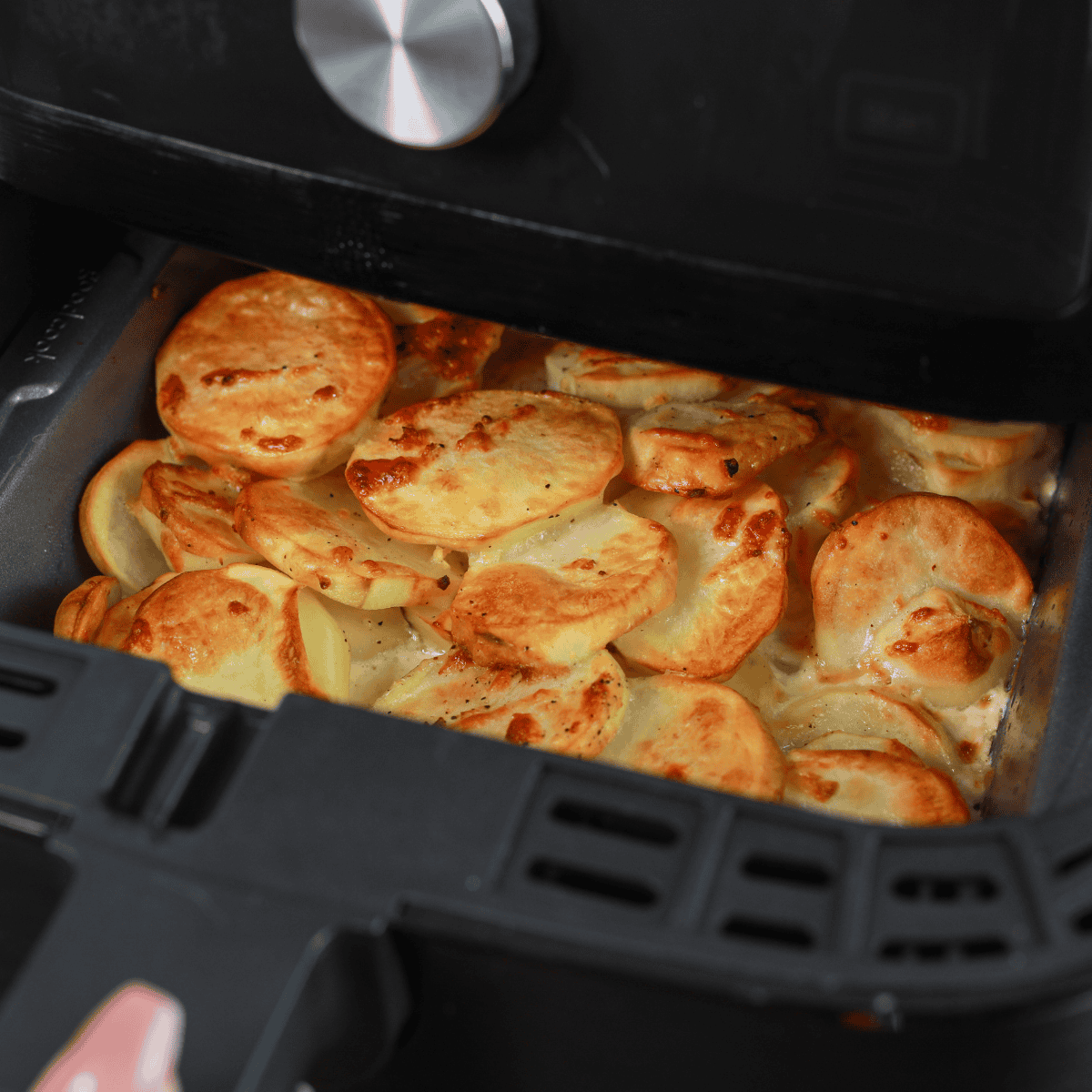 Potatoes evenly arranged in greased air fryer pan ready to cook at 330°F