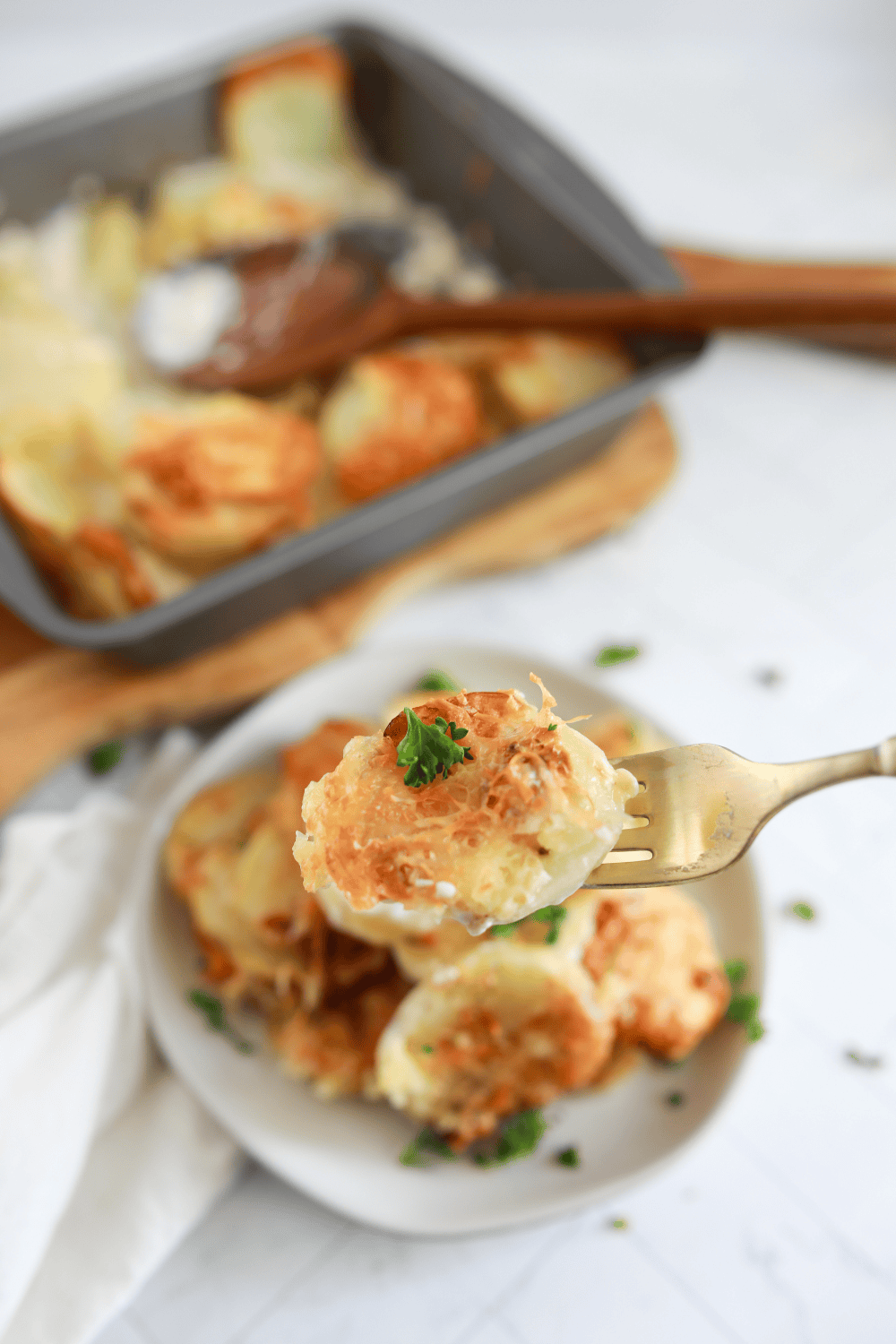 Portion of cheesy au gratin potatoes plated with fresh herbs