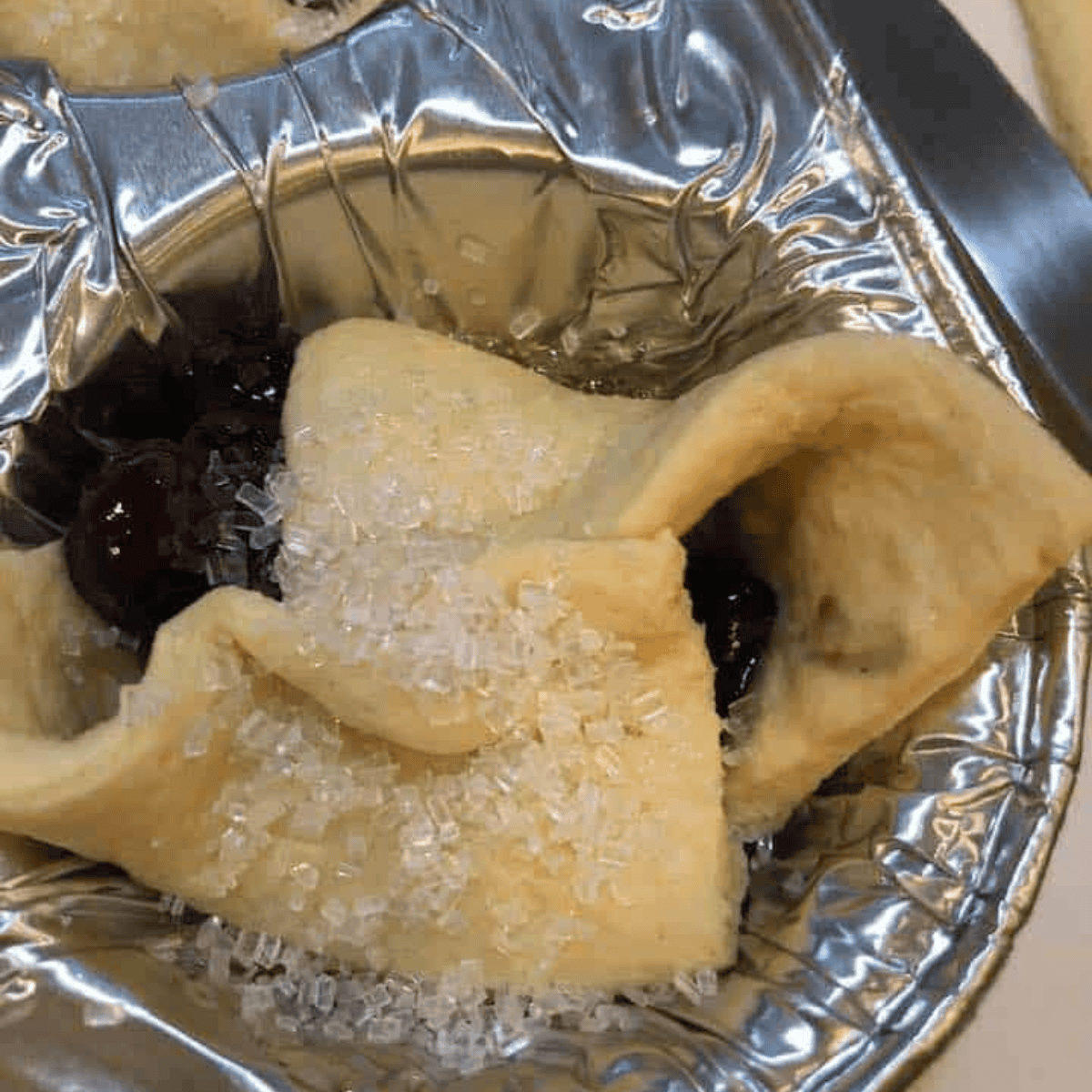 Sprinkling sugar on blueberry crescent roll muffins and air frying until golden brown