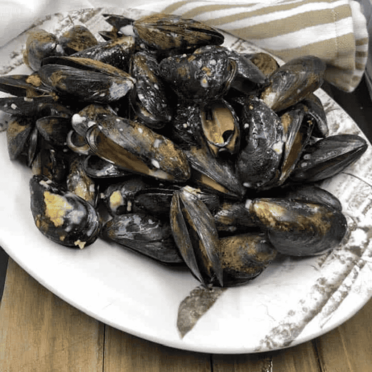 Golden mussels in garlic herb butter served in a bowl, cooked in an air fryer