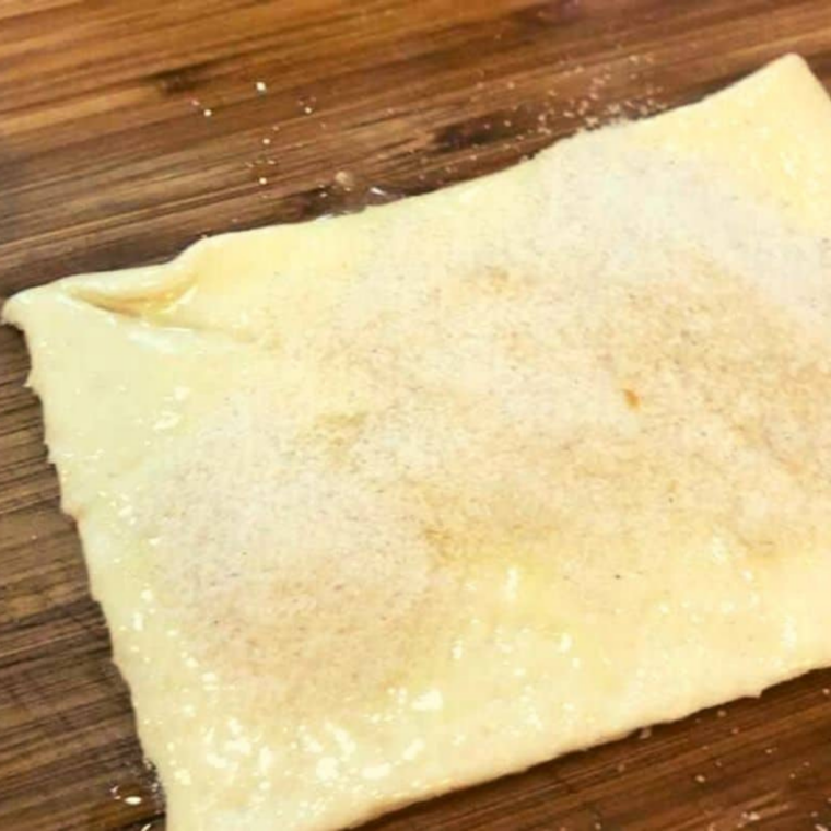 Lightly greased air fryer basket lined with parchment paper, ready for crescent roll dough preparation.