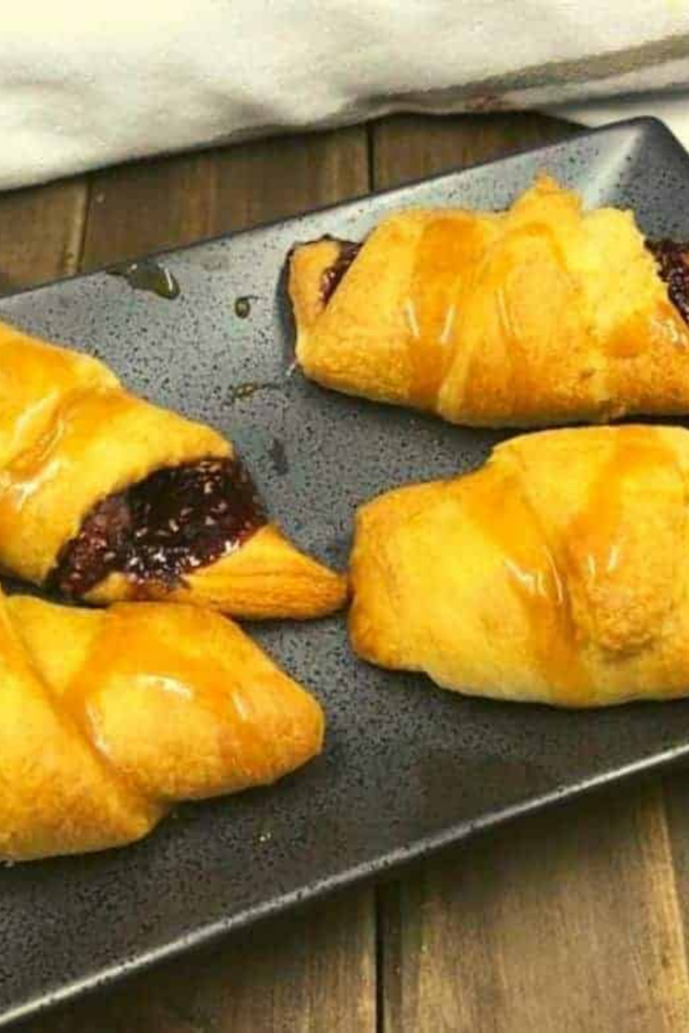Flaky air fryer raspberry crescent rolls filled with raspberry jam on a serving plate