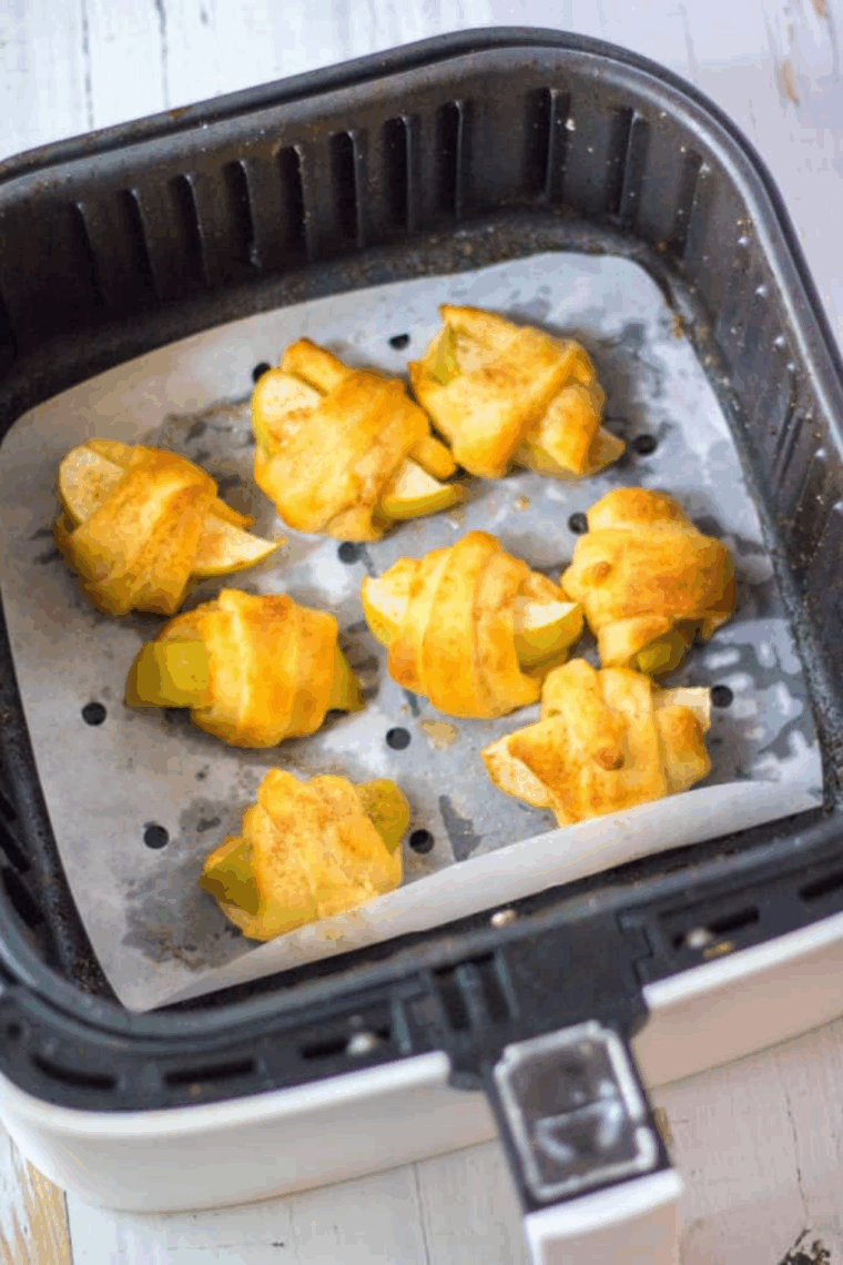 Apple crescent rolls being brushed with melted butter and sprinkled with cinnamon sugar.