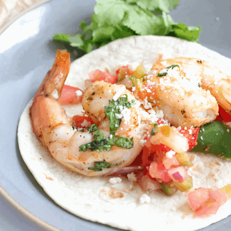 Air fryer basil pesto shrimp kebobs on wooden skewers with charred pesto edges and lemon wedges