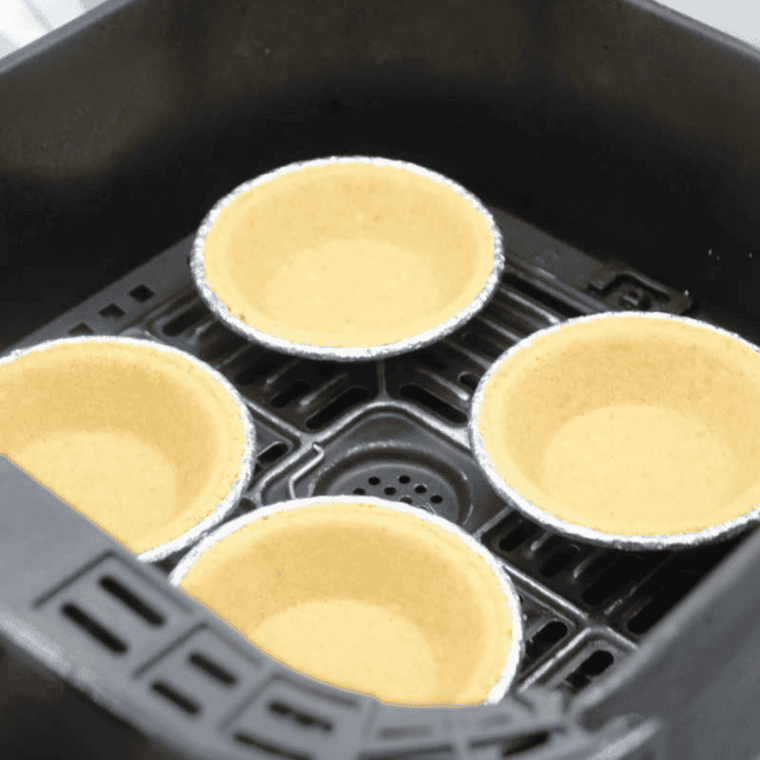 Placing pie crusts in air fryer basket and lightly pre-cooking at 300°F