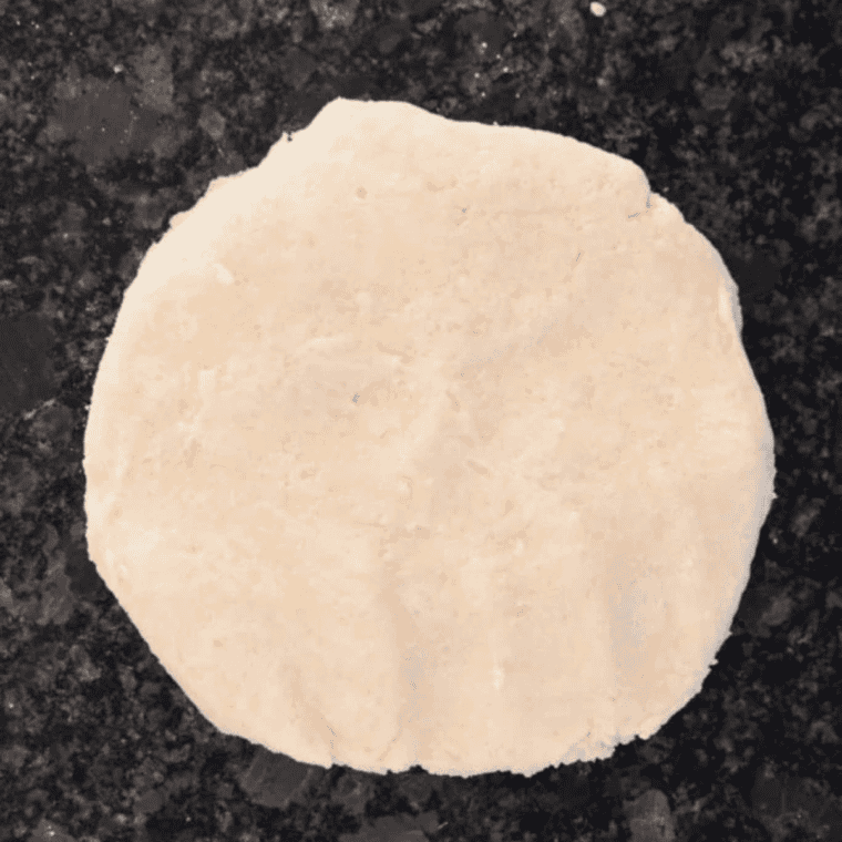 Apple galette pastry shaped into a disk and wrapped in plastic to chill